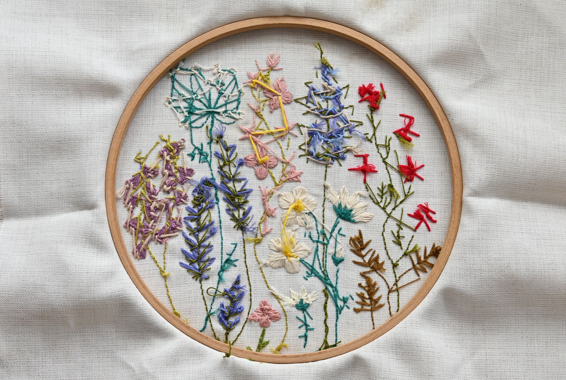 Vibrant needlework of wildflowers on fabric in a wooden hoop.