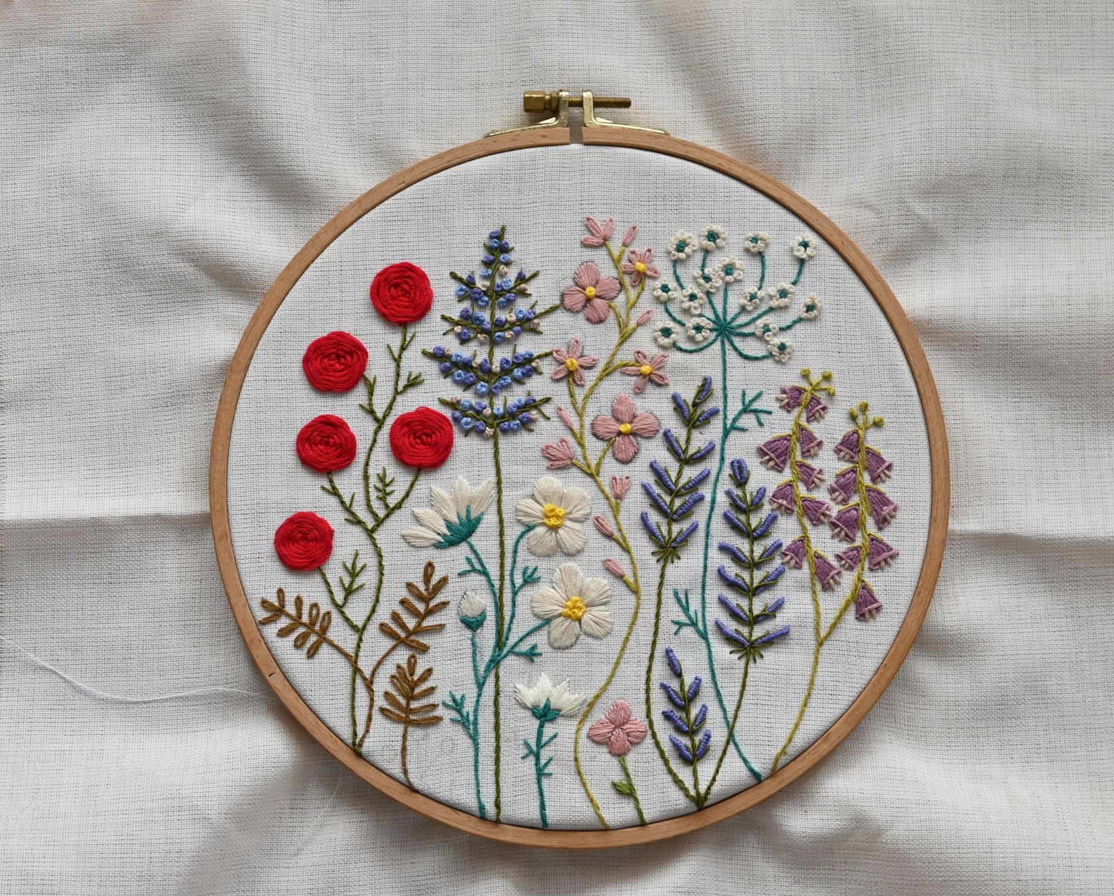 Vibrant handcrafted floral embroidery showcased in a wooden hoop on fabric.