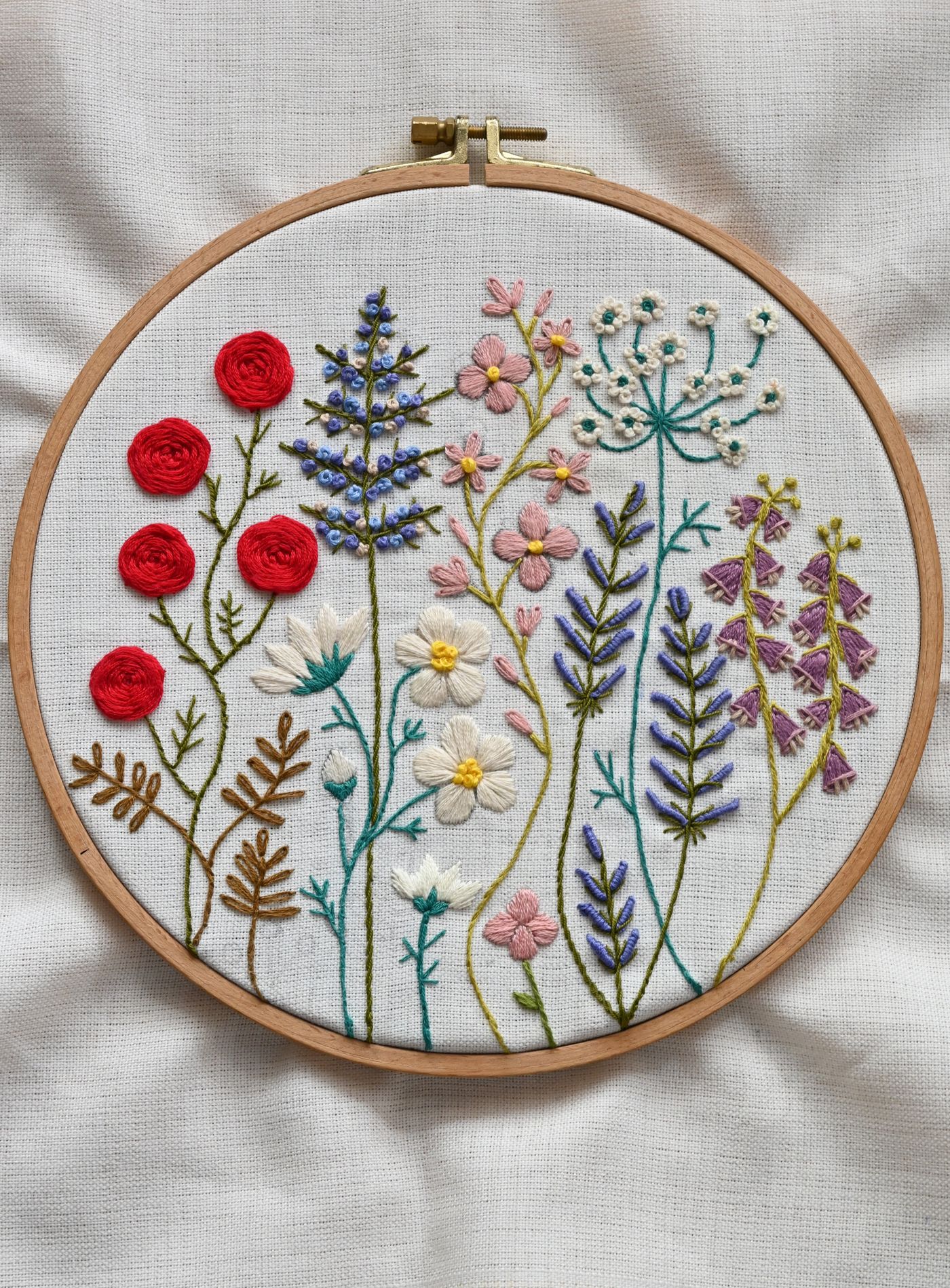 Wildflower embroidery in a wooden hoop with red, lavender and cream stitching