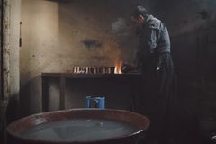 An artisan skillfully works on metalware in a rustic workshop, showcasing traditional crafting.