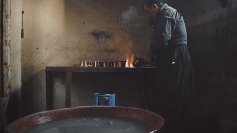 An artisan skillfully works on metalware in a rustic workshop, showcasing traditional crafting.