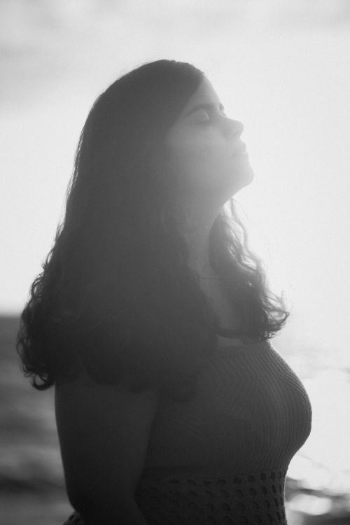 Free A silhouette of a woman on a beach during sunset, capturing a serene and dramatic mood. Stock Photo