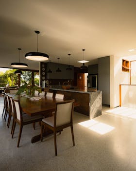 Spacious modern kitchen with wood accents and natural light. Sleek minimalist decor and dining area with subtle luxury.