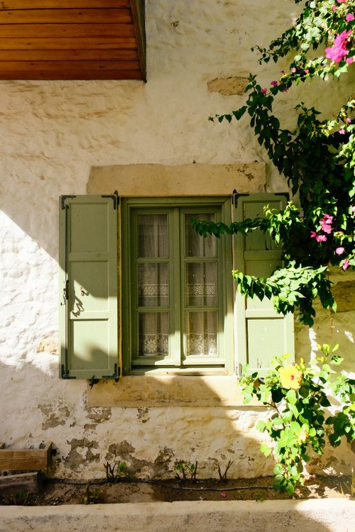 Free Rustic window with green shutters surrounded by vibrant flowers in İzmir, Türkiye. Stock Photo