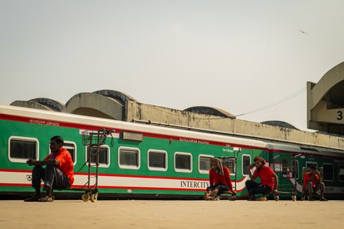 Free Workers take a break near a Bangladesh Railway intercity train, showcasing daily life at a railway station. Stock Photo