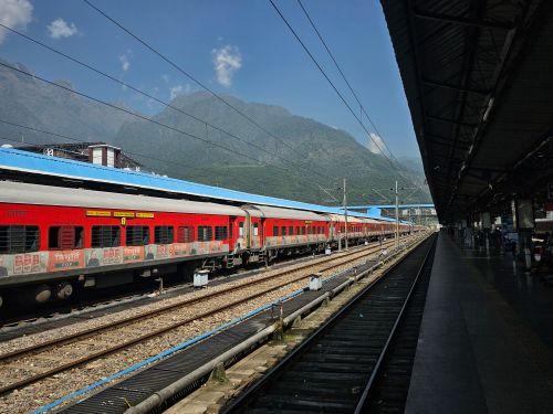 Free A vibrant red train at an outdoor station with scenic mountain backdrop, ideal for travel themes. Stock Photo