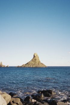 Beautiful coastal view of Cyclopean Isles off Sicily's coast, with clear blue skies.