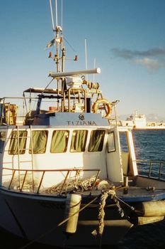 Vintage photo of a fishing boat docked in a Sicilian marina, capturing a classic maritime scene.