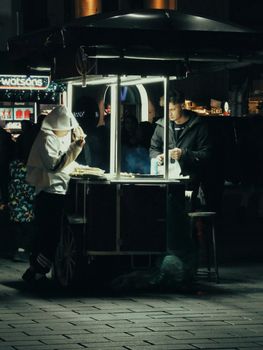 Street food vendor and customers during evening in bustling Istanbul.