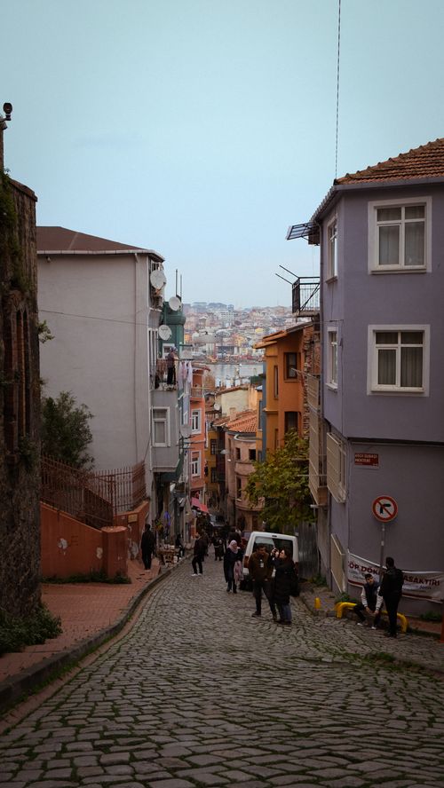 Free Picturesque view of a cobblestone street in Balat, Istanbul, with colorful buildings and people walking. Stock Photo