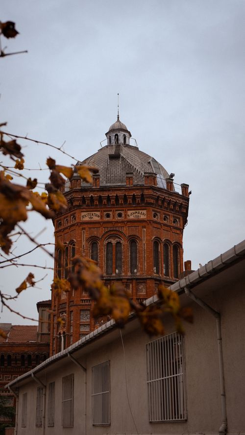 Free Beautiful red brick tower framed by autumn leaves, showcasing historic architecture. Stock Photo
