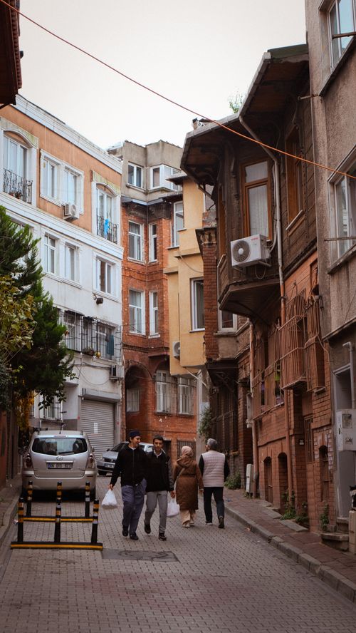 Free A narrow street in Istanbul featuring historical buildings and local residents walking. Stock Photo