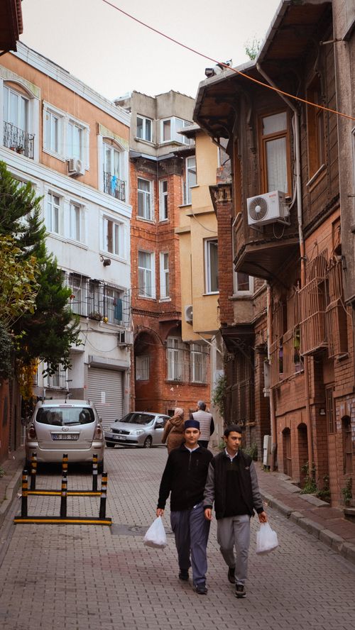 Free Two men walking on a quaint street lined with historic architecture. Stock Photo