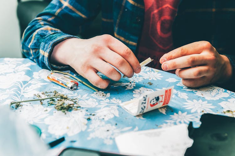 Person Rolling A Paper With Weed