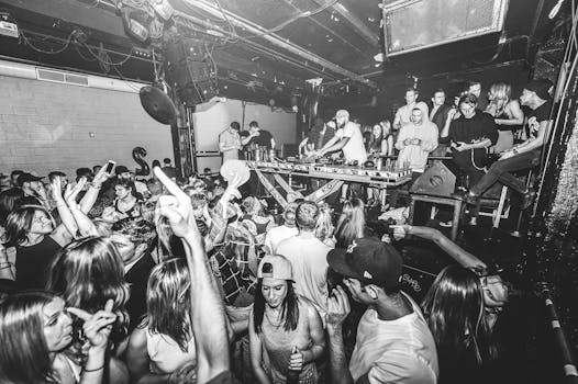 Vibrant nightclub scene with DJ and dancing crowd enjoying live music.
