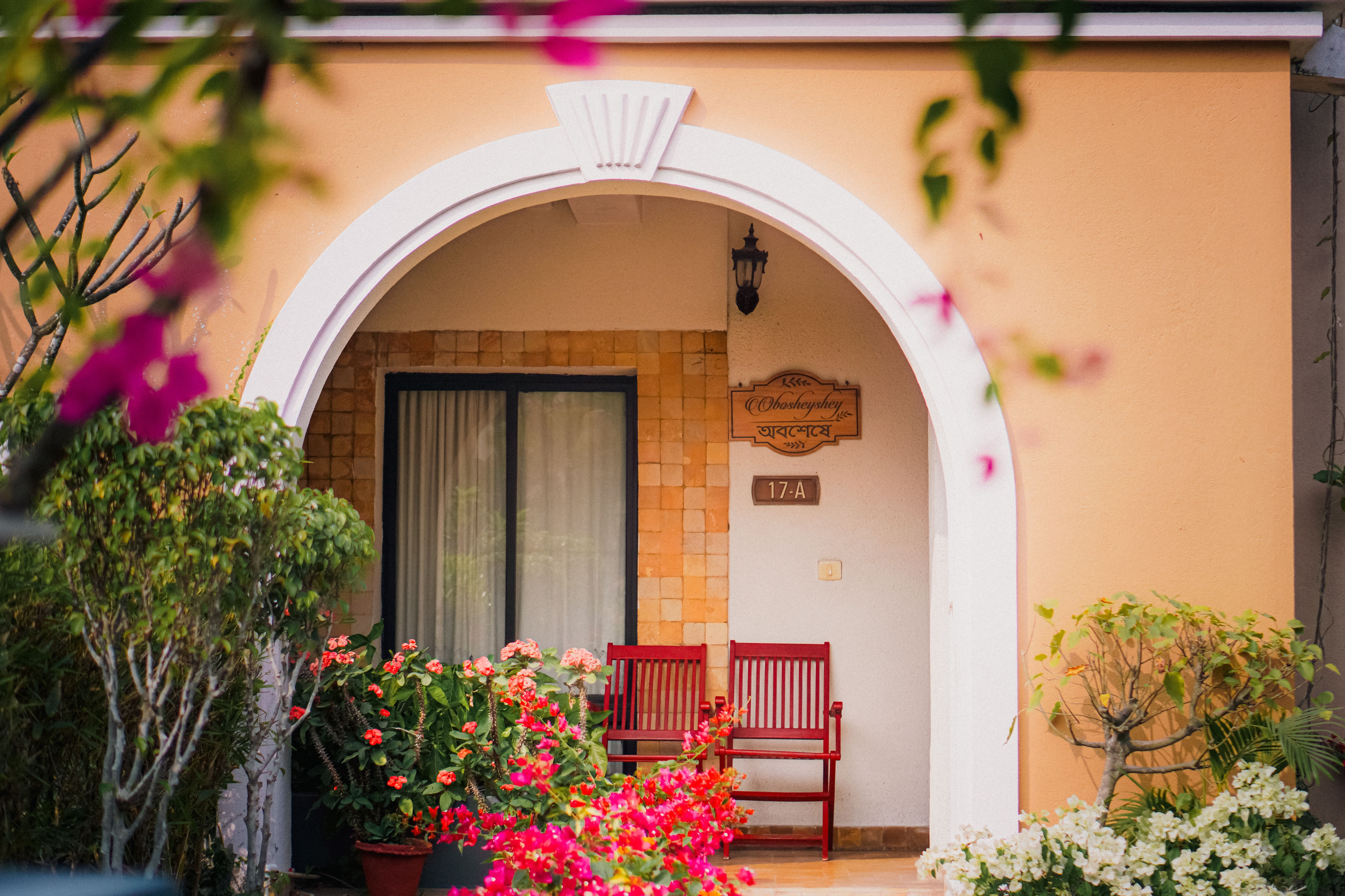 Charming home entrance framed by colorful blooming flowers and an inviting bench, capturing the warmth of home