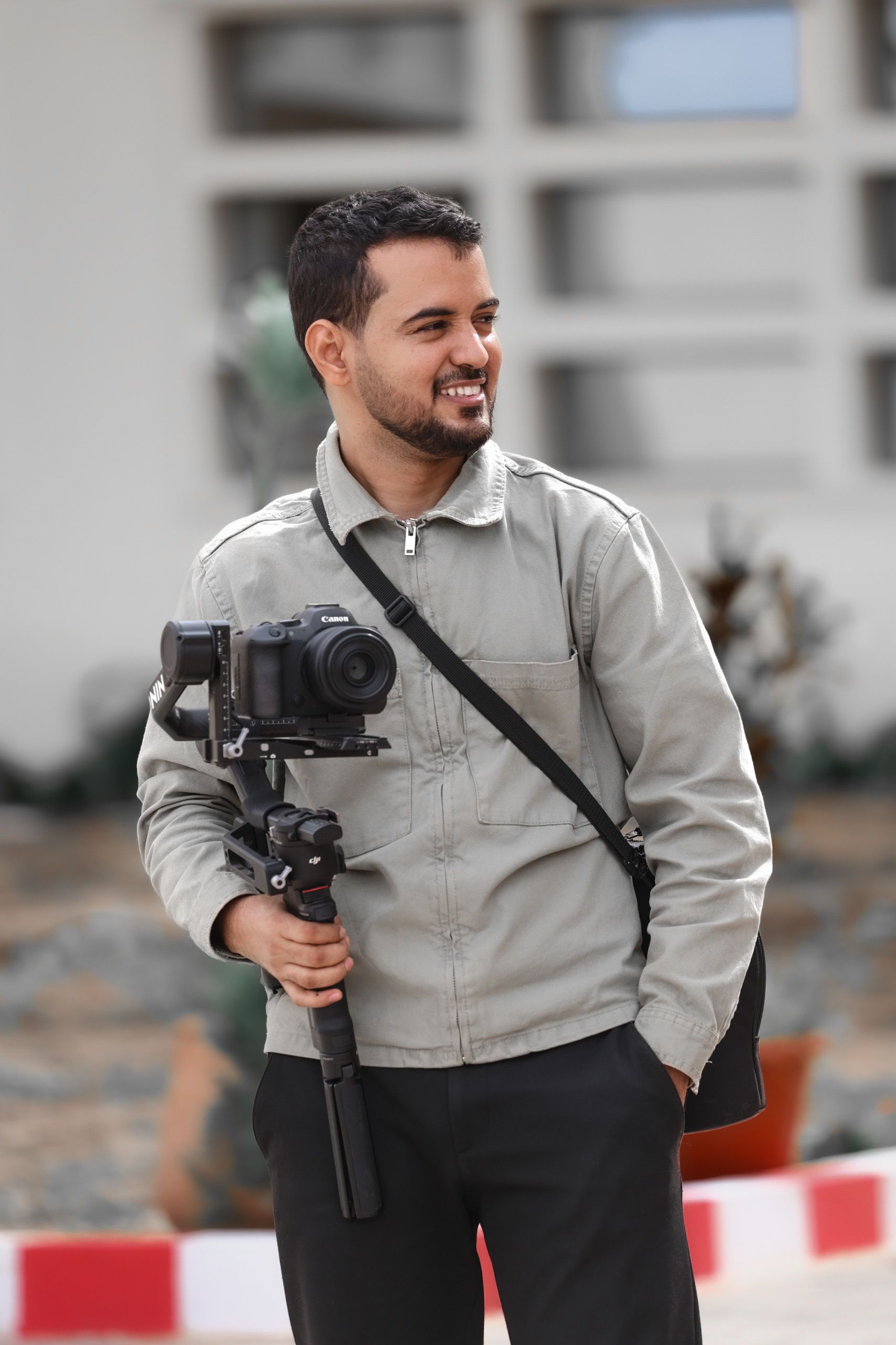 Smiling photographer holding a camera on a gimbal outdoors in Nouakchott, Mauritania.