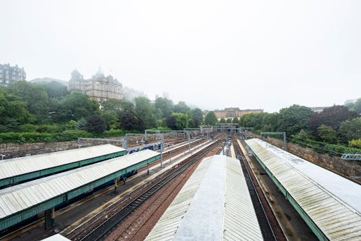 Misty morning view of train tracks and classic buildings in Edinburgh, Scotland.