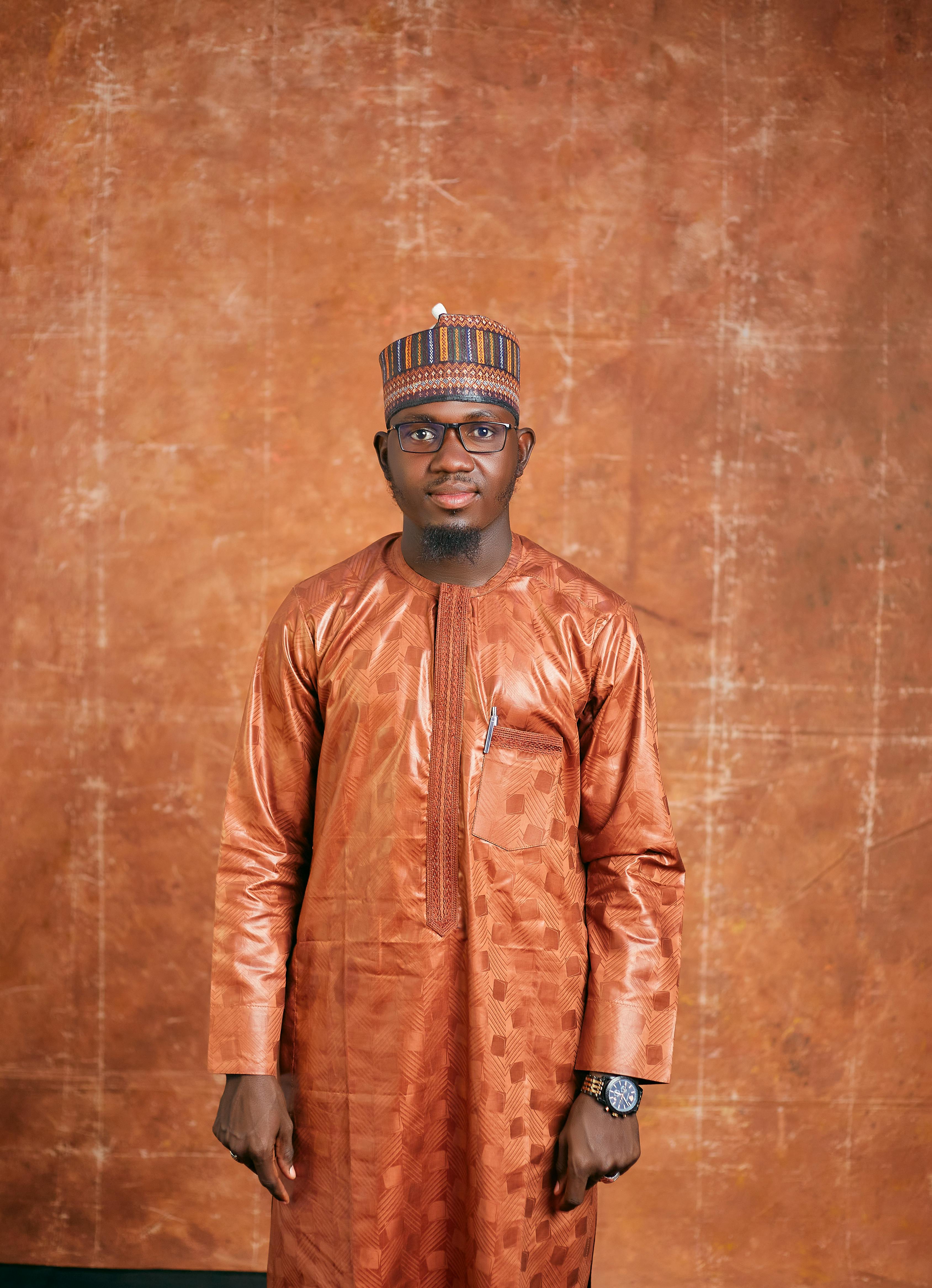 Portrait of an African man wearing traditional attire with a matching hat indoors.