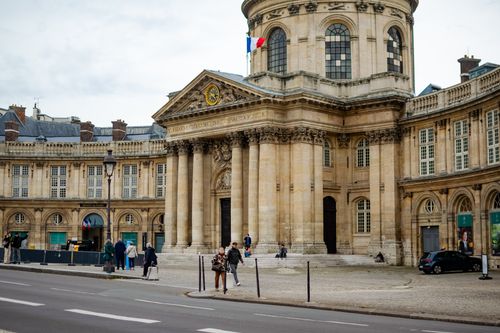 Free Elegant historic building in Paris featuring classic architecture and French flag. Stock Photo