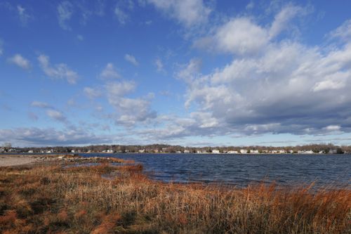 Free Picturesque lake scene with grassy shoreline under a partly cloudy sky, ideal for nature themes. Stock Photo