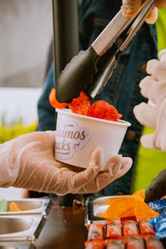 Street vendor serving red flavored crisps in a white cup at a snack stall, close-up view.