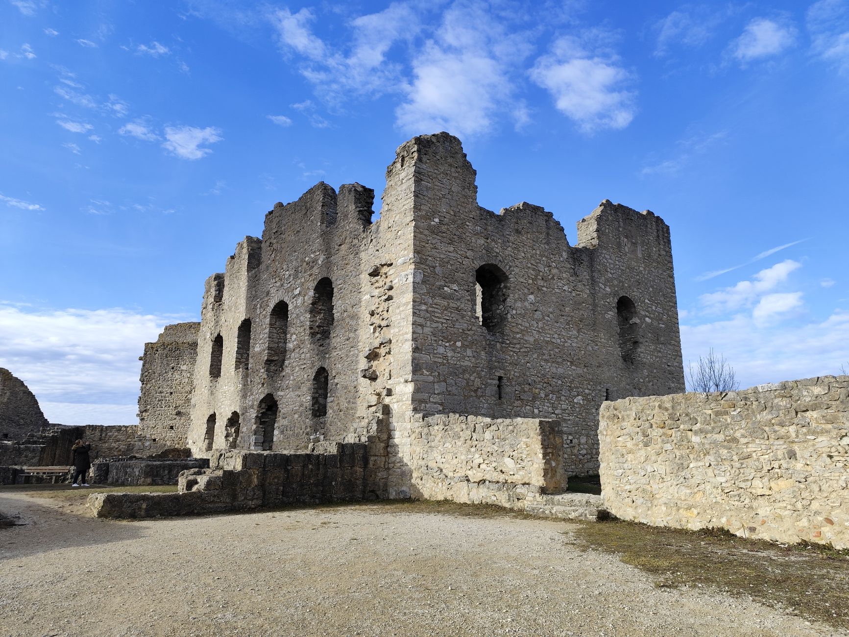 Explore the historic stone ruins of a medieval castle under a vibrant blue sky.