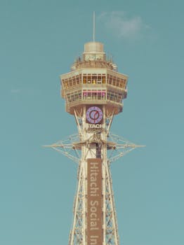 Vintage-style image of Tsutenkaku Tower, Osaka, with a clear blue sky background.
