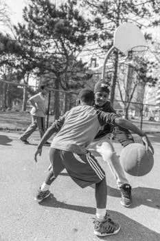 两个男孩在户外球场上激烈地打篮球，展现了团队合作和运动能力