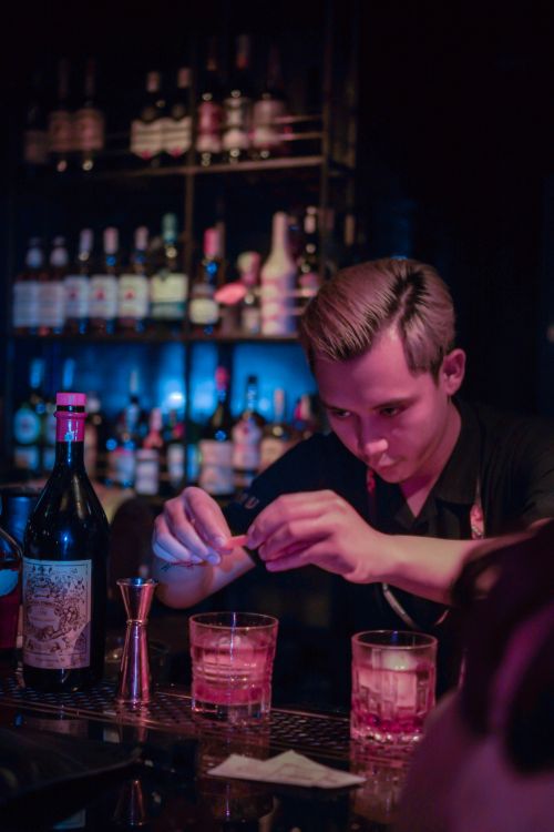 Free A focused bartender skillfully prepares a cocktail in a cozy, dimly lit bar setting. Stock Photo