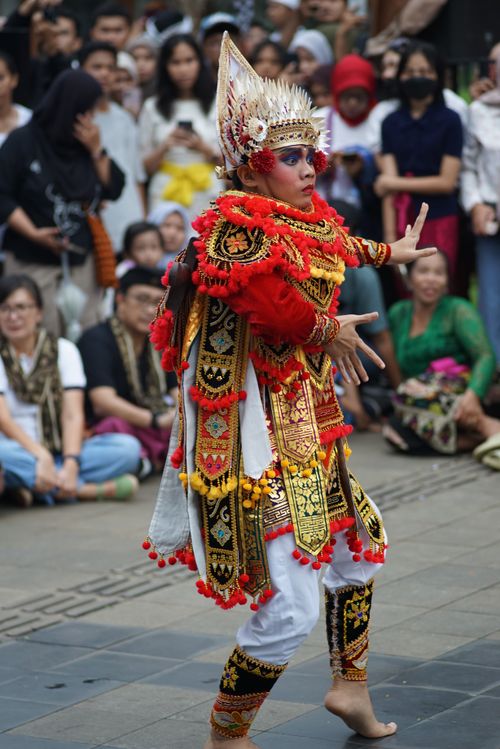 Free Colorful Balinese dancer performing outdoors in traditional attire before an engaged audience. Stock Photo
