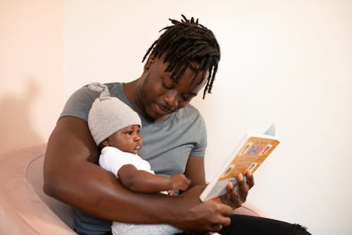 Un Hombre Leyendo Un Libro A Su Bebé