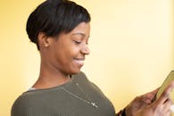 一名妇女在柔和的黄色背景下微笑着使用智能手机