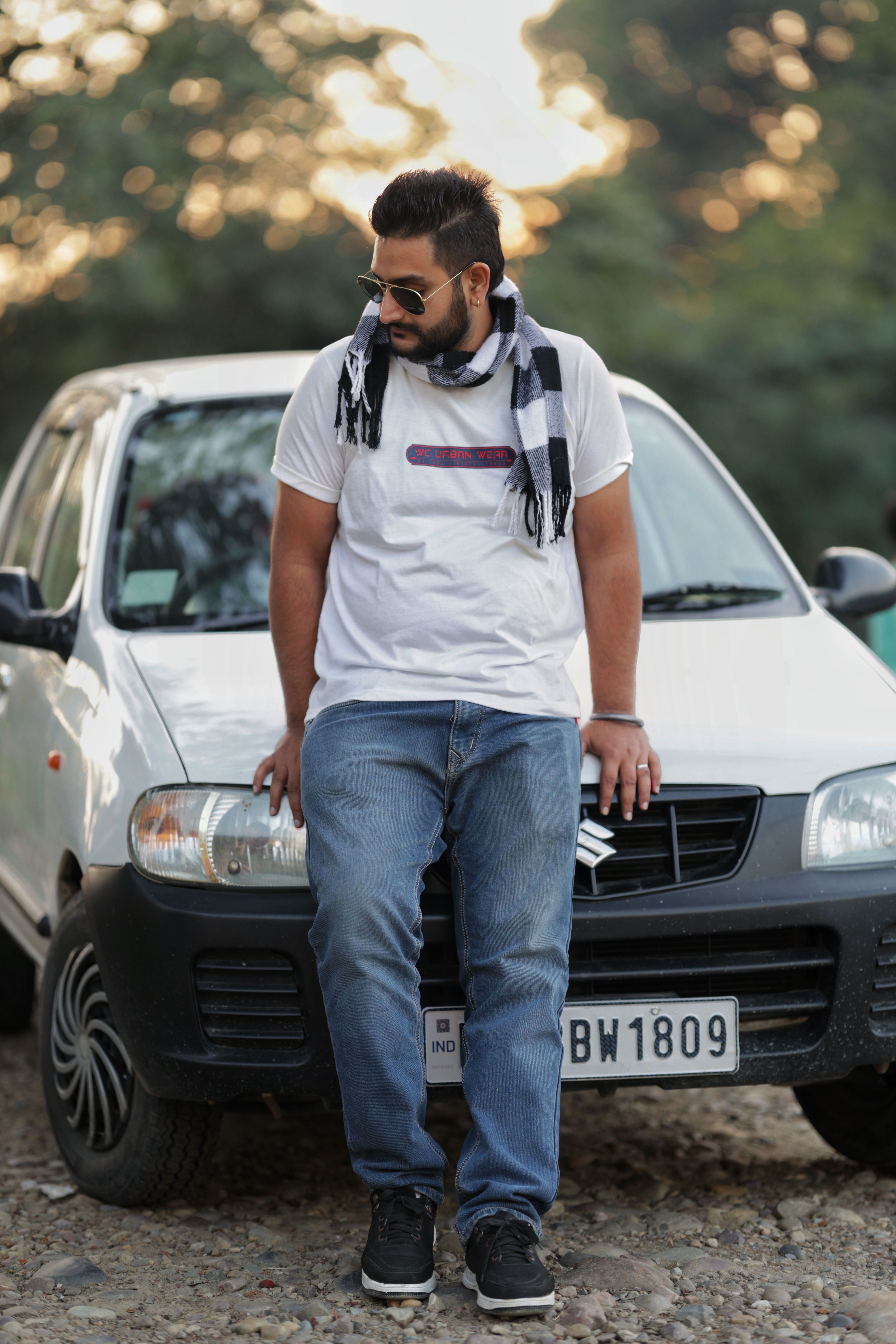 Man in casual attire posing with a car outdoors in Bankhandi, Himachal Pradesh, India.