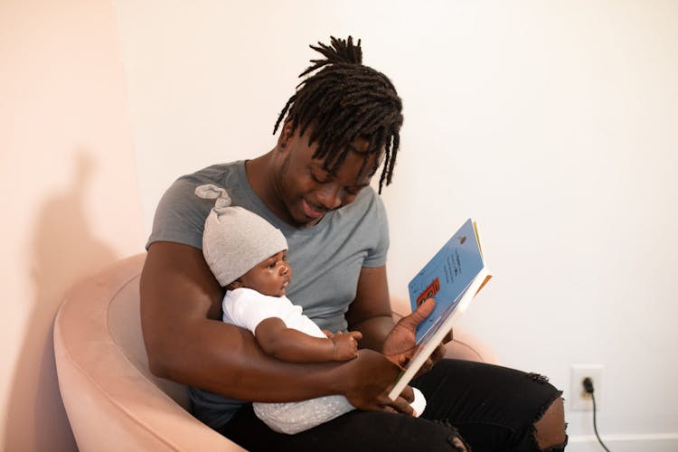 A Father Reading A Book To His Baby