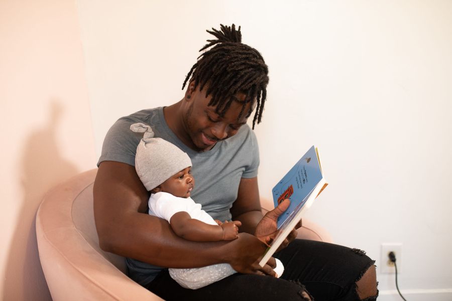 Pai lendo um livro pro bebê no colo