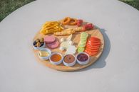 A vibrant Turkish breakfast platter with assorted foods served on a wooden board outdoors.