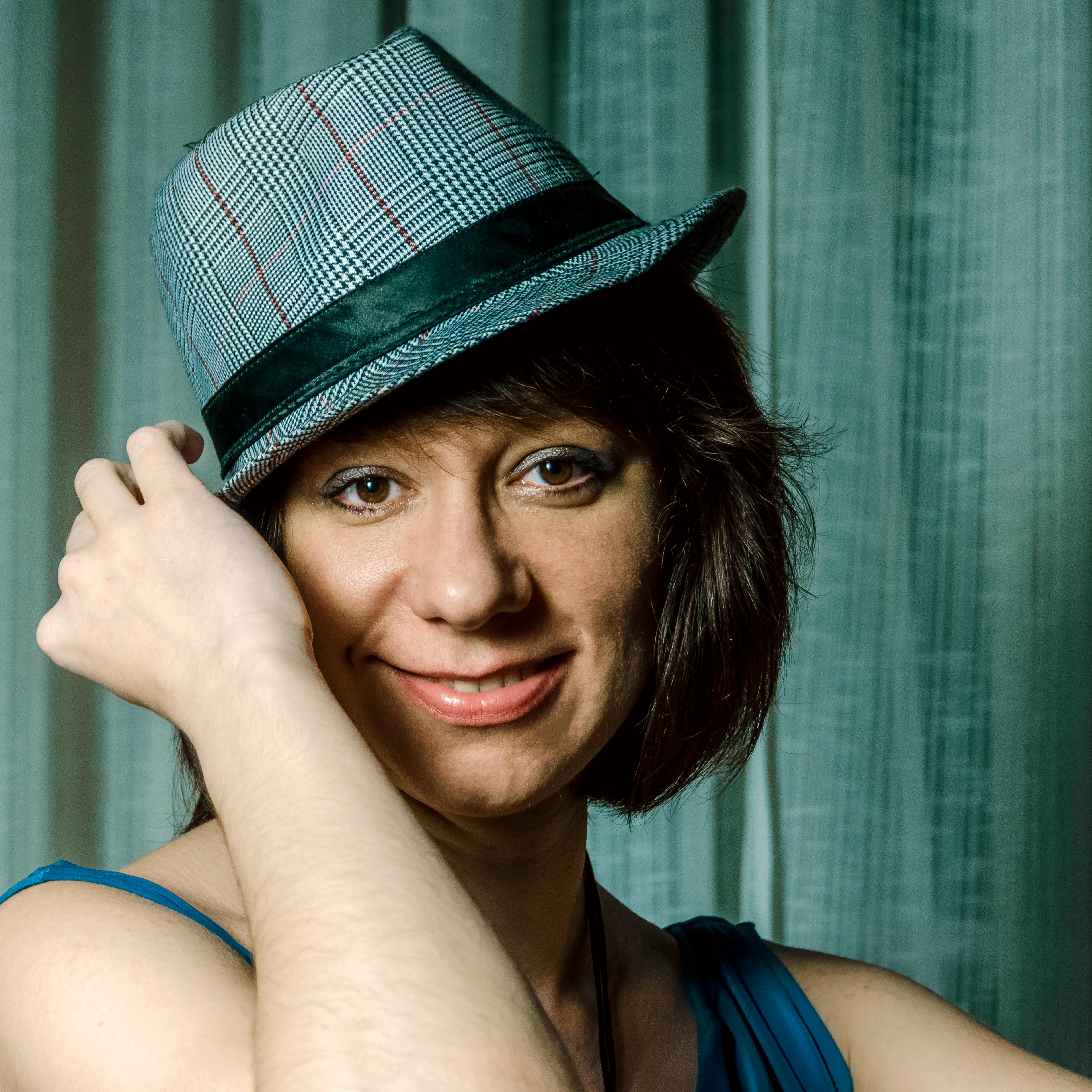 Free Candid portrait of a woman with a blue fedora, showcasing a friendly smile. Stock Photo