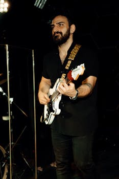 Guitarist with beard playing electric guitar during a live concert performance.