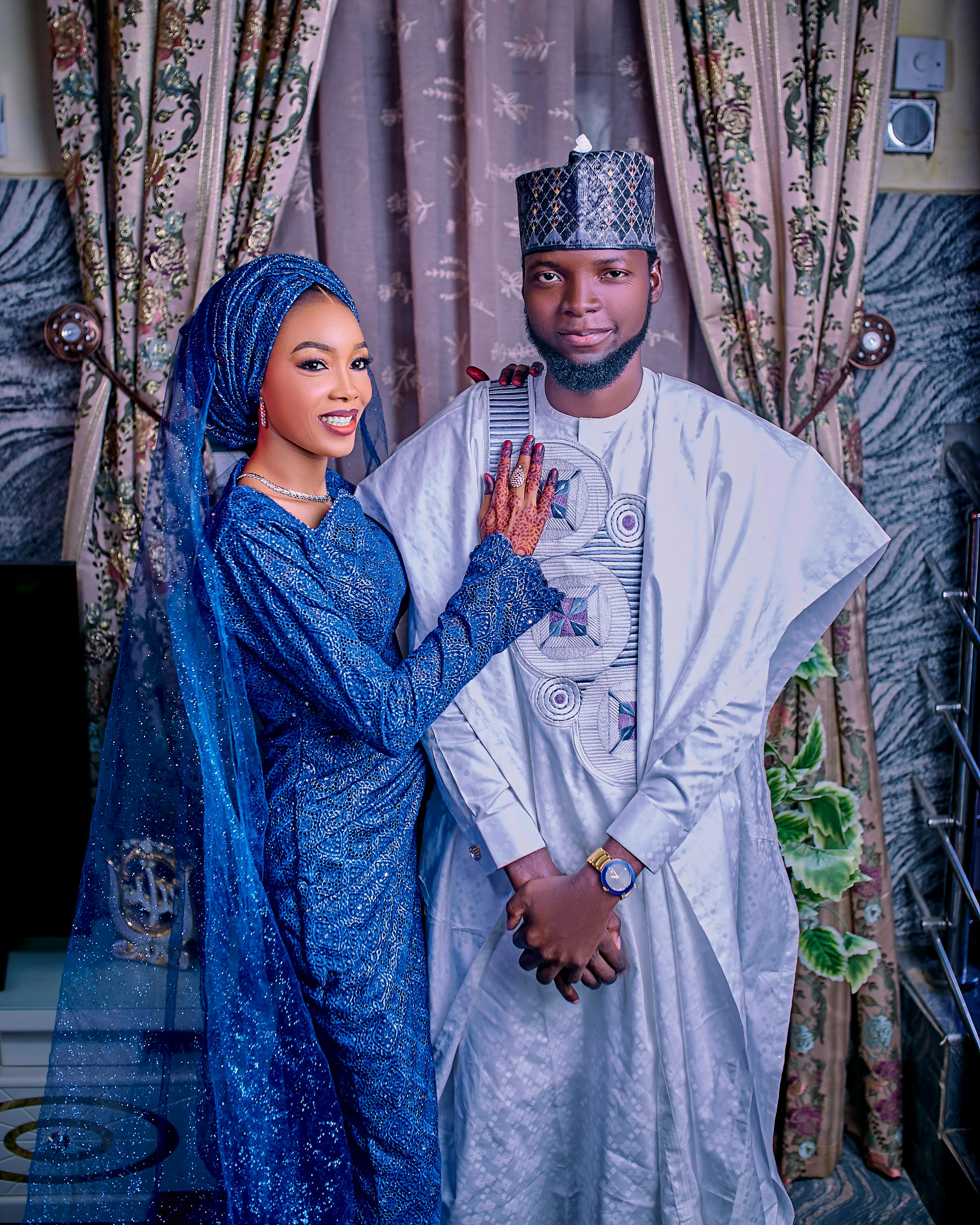 Elegant couple in traditional African attire posing indoors for a portrait.