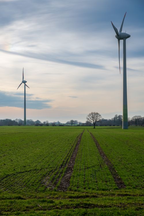 Free Two wind turbines stand in a lush green field at dusk, generating renewable energy. Stock Photo