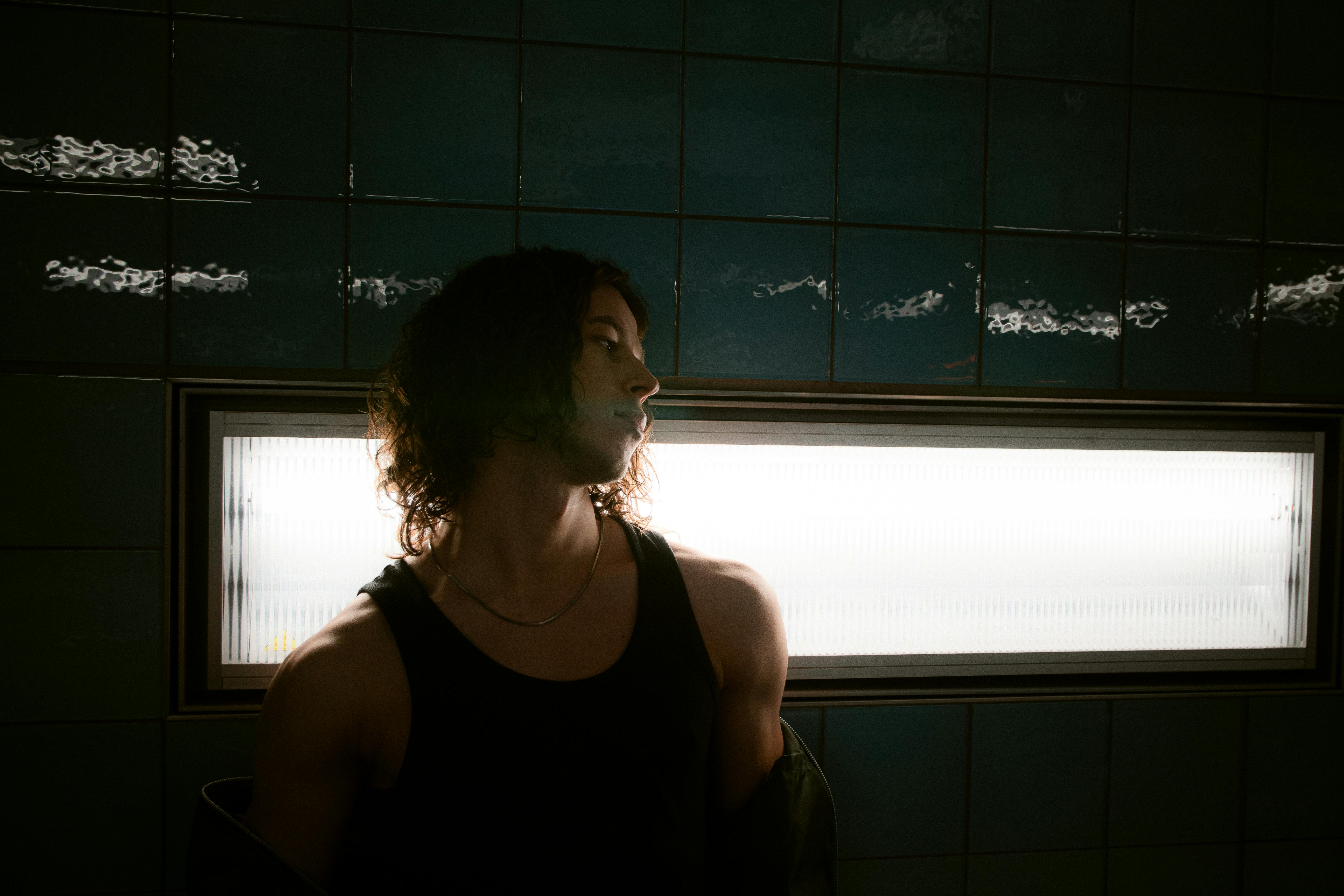 Kostenlos Ein stimmungsvolles Porträt einer Person in einer schwach beleuchteten Hamburger U-Bahn-Station. Stock-Foto