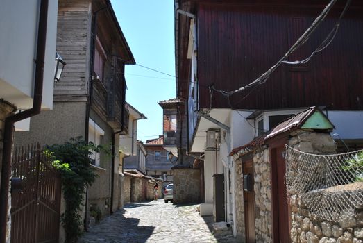 Quaint cobblestone street flanked by rustic wooden houses in a historical town.
