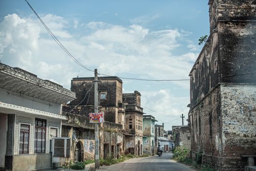 A quiet street lined with historic buildings in a rural town in India, under a clear blue sky.