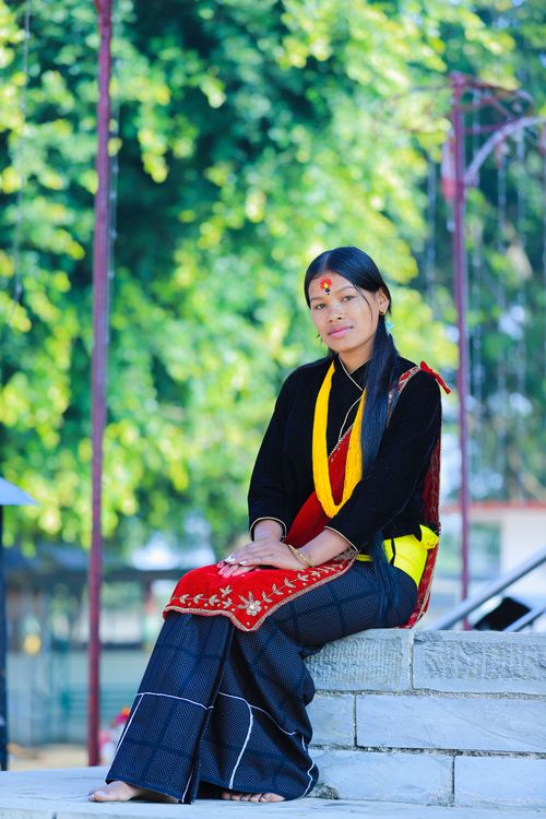 Free A woman in colorful traditional clothes sitting outdoors, showcasing cultural heritage. Stock Photo