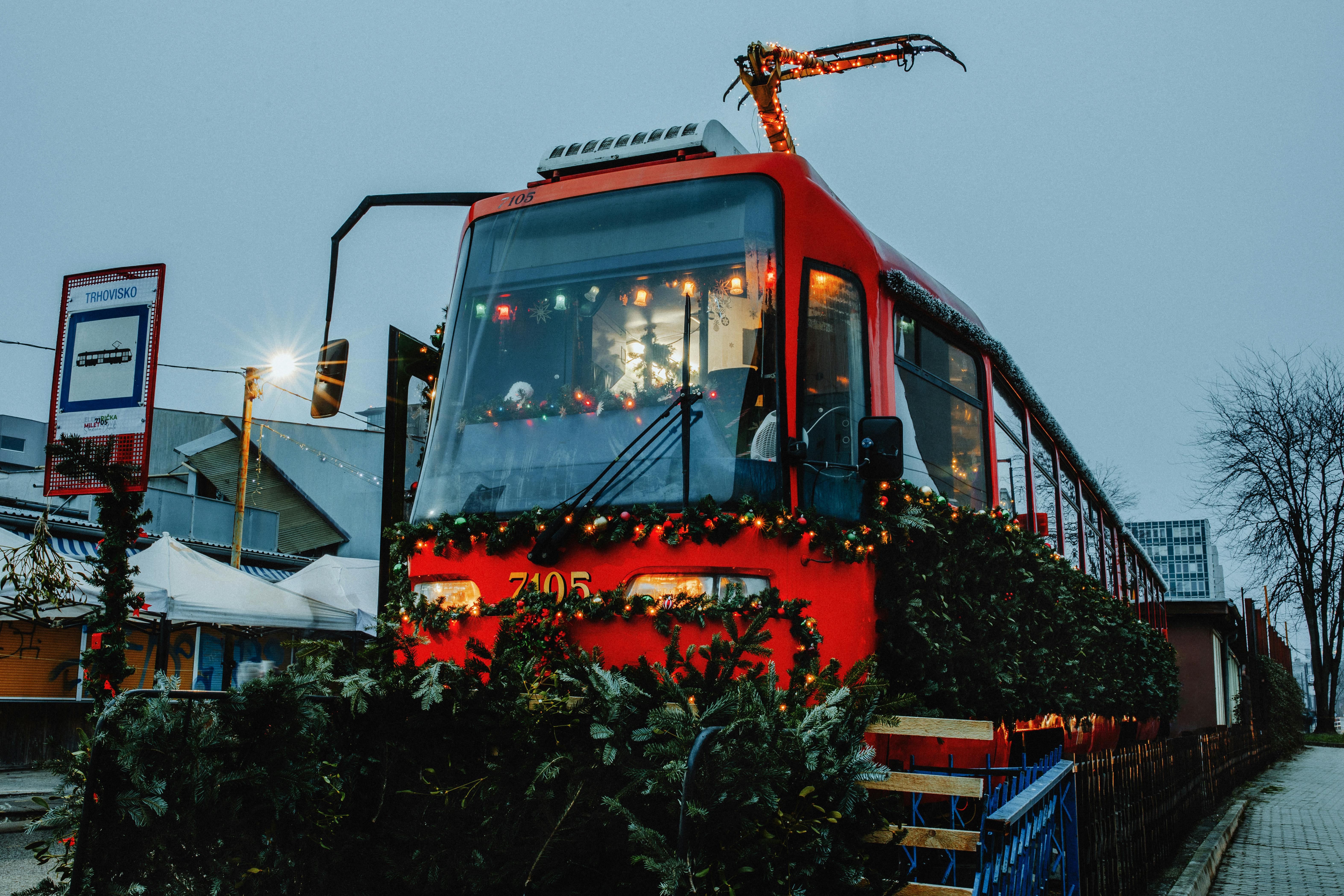A red tram adorned with Christmas decorations and lights during a festive season in a city setting.