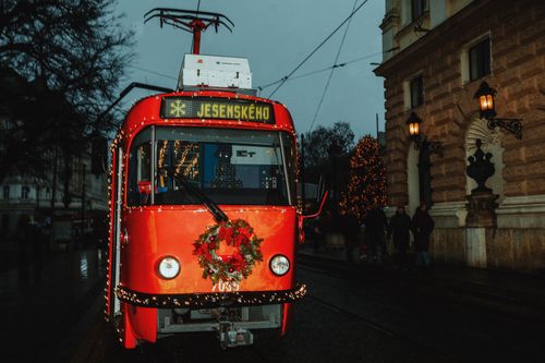 Free Red tram decorated for Christmas with lights and wreath in winter city setting. Stock Photo