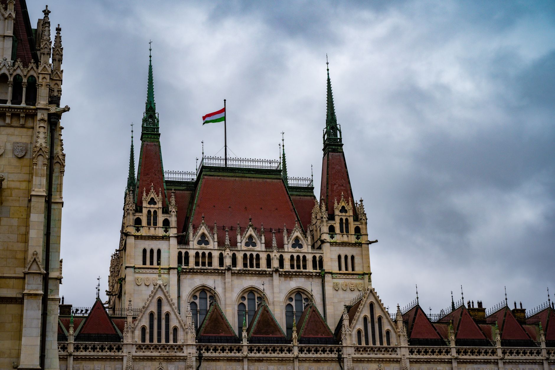 Gothic revival architecture of the Hungarian Parliament Building topped with the national flag in Budapest.
