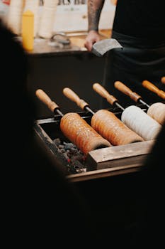 Kürtőskalács baking over open coals in Hungary, showcasing a classic street food preparation.