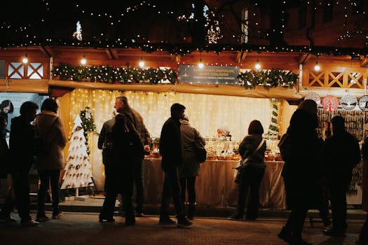 People browsing festive stalls at a nighttime holiday market in Budapest.
